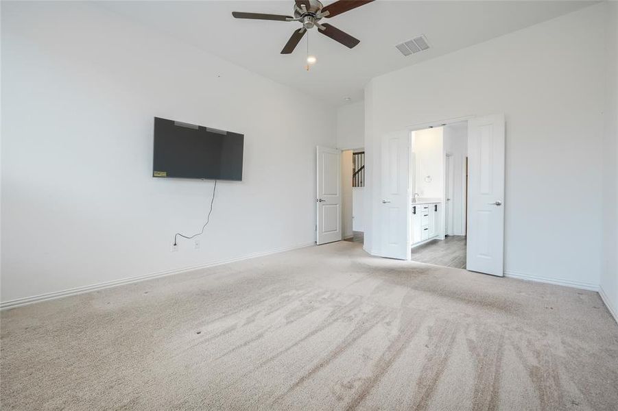 Unfurnished bedroom featuring light colored carpet, ceiling fan, and connected bathroom Unfurnished bedroom featuring light colored carpet, ceiling fan, and connected bathroom