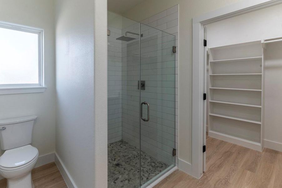 Full bathroom with light wood finished floors, a stall shower, and a spacious closet