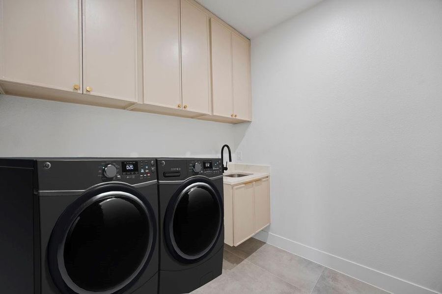 Laundry area with cabinets, sink, separate washer and dryer, and light tile patterned floors