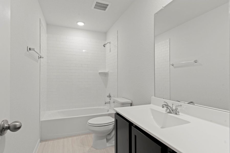 The upstairs bathroom features a sleek vanity, tub and shower combination, and elegant tile flooring. A clean and functional design ideal for guests%
