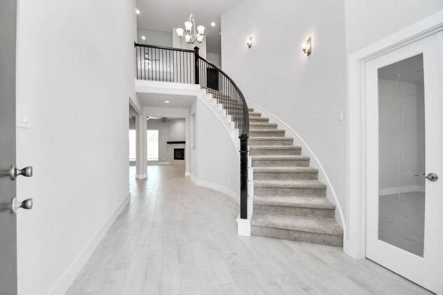 As you step into the threshold of this luxurious home, you'll soon be welcomed by an elegant glass door (to be installed). Inside, soaring ceilings amplify the spaciousness, while the refined wood-look tile flooring and oversized baseboards exude sophistication and charm. Sample photo of completed home with similar floor plan. Actual colors and selections may vary.