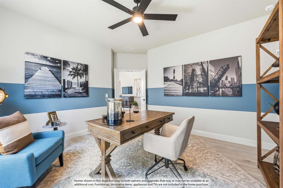 Home office with wood desk, ceiling fan, blue accent walls, and black-and-white wall art