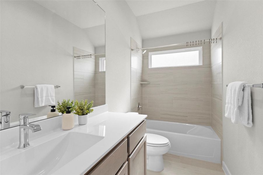 Your full bathroom features a sleek vanity, large mirror, tub/shower combination with tiled surround, and a transom-style window. Your full bathroom features a sleek vanity, large mirror, tub/shower combination with tiled surround, and a transom-style window.