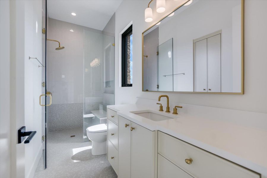 A refined bathroom featuring a spacious walk-in shower with bench and a sleek vanity.