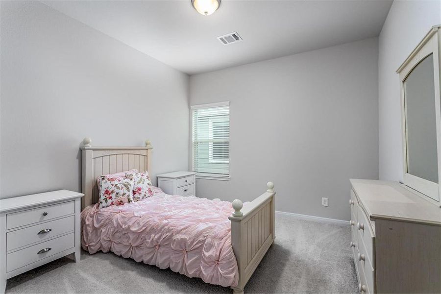 A cozy and charming secondary bedroom perfect for guests or family members. The soft, neutral color palette and plush carpeting create a calming atmosphere, while the large window allows for ample natural light. A versatile space that can be easily personalized to suit any style or need. **This image is from another Saratoga Home - Mockingbird floorplan.**