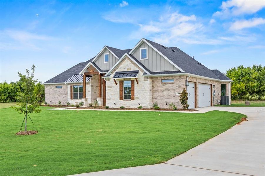 View of front of house featuring board and batten siding, concrete driveway, a front yard, roof with shingles, and stone siding View of front of house featuring board and batten siding, concrete driveway, a front yard, roof with shingles, and stone siding