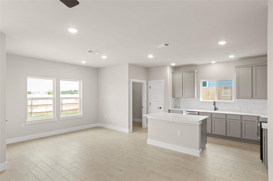 Kitchen with gray cabinetry, backsplash, recessed lighting, a sink, and a center island Kitchen with gray cabinetry, backsplash, recessed lighting, a sink, and a center island