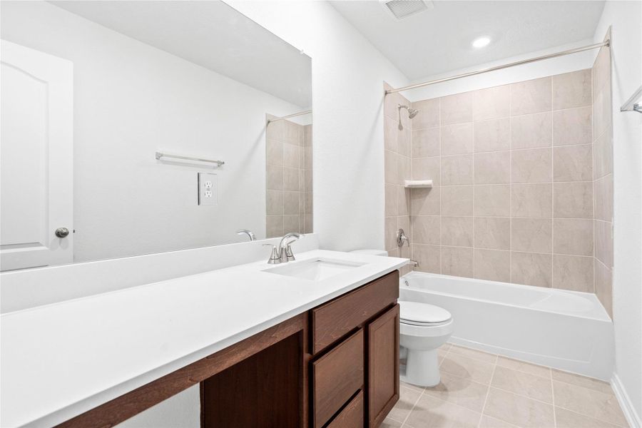 The secondary bathroom showcases tile flooring, a bath/shower combo with Daltile tile surround, a vanity with knee space, a stunning light countertop, a large mirror, sleek fixtures, and contemporary finishes throughout. The secondary bathroom showcases tile flooring, a bath/shower combo with Daltile tile surround, a vanity with knee space, a stunning light countertop, a large mirror, sleek fixtures, and contemporary finishes throughout.
