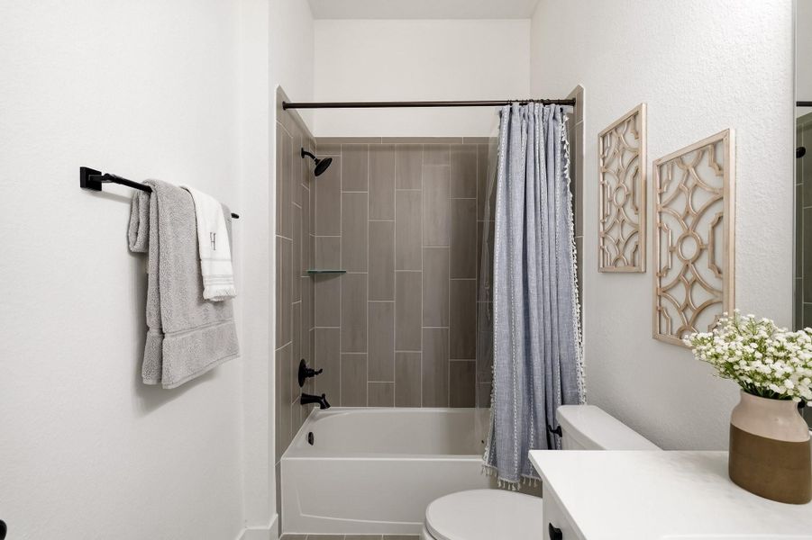 A combination tub/shower framed by a stylish tile surround completes the bath with a refined, cohesive finish.