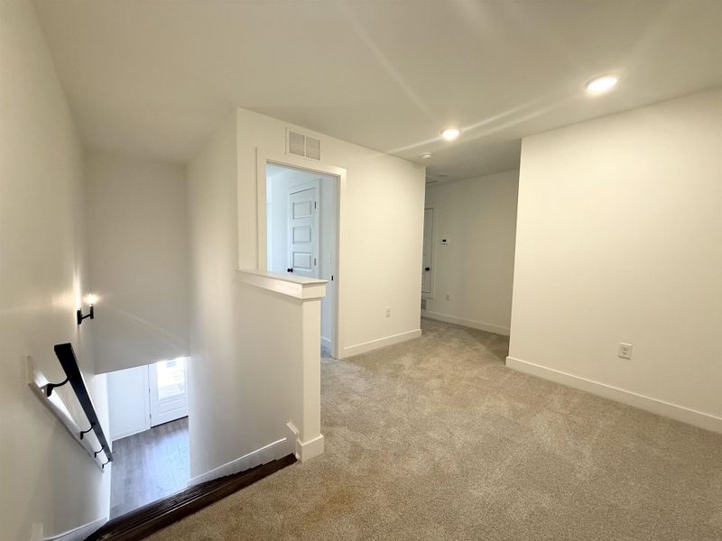 Hall featuring an upstairs landing, carpet flooring, and recessed lighting