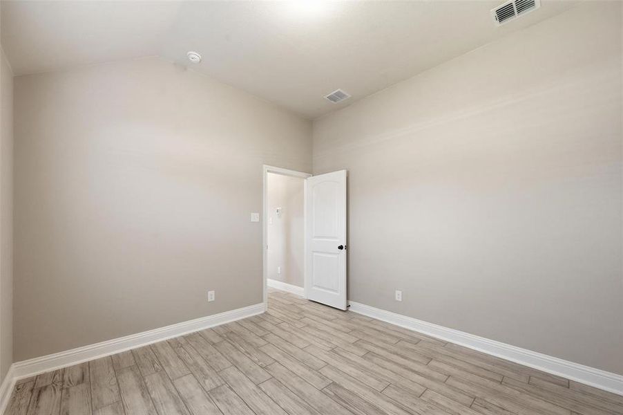 Spare room featuring vaulted ceiling and light wood-style floors Spare room featuring vaulted ceiling and light wood-style floors