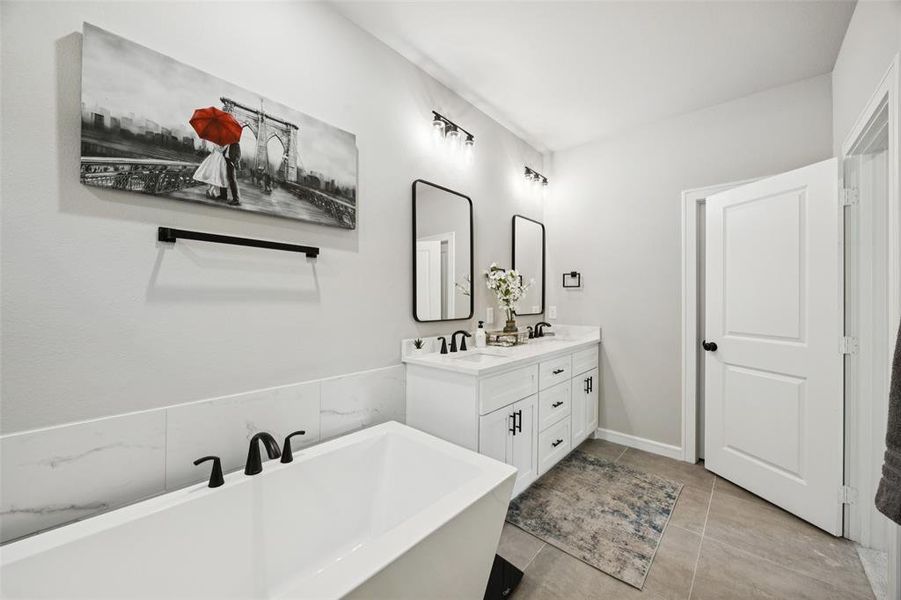 Bathroom featuring a freestanding tub, double vanity, and light tile patterned floors