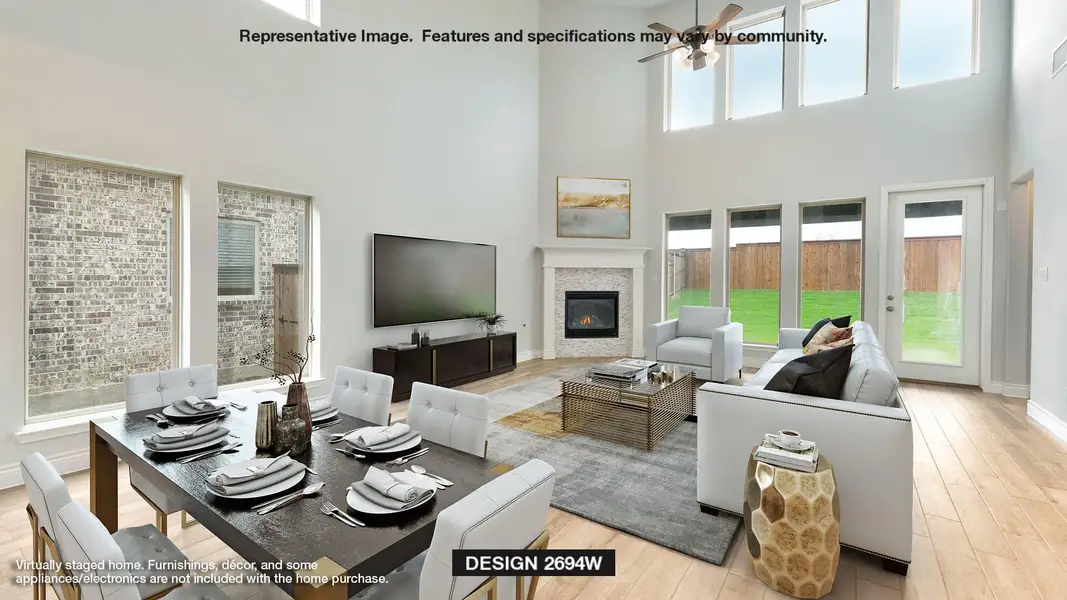 Living area featuring a ceiling fan, a high ceiling, a glass covered fireplace, and wood finished floors