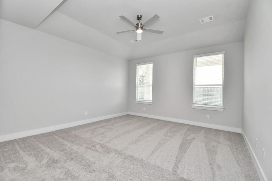 Come and unwind after a long day in this magnificent primary suite! This spacious room features plush carpet, warm paint, high ceilings and large windows with privacy blinds. Sample photo of completed home with similar floor plan. Actual colors and selections may vary.