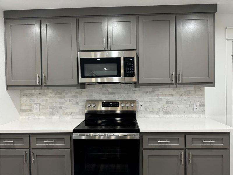 Kitchen with gray cabinetry and appliances with stainless steel finishes