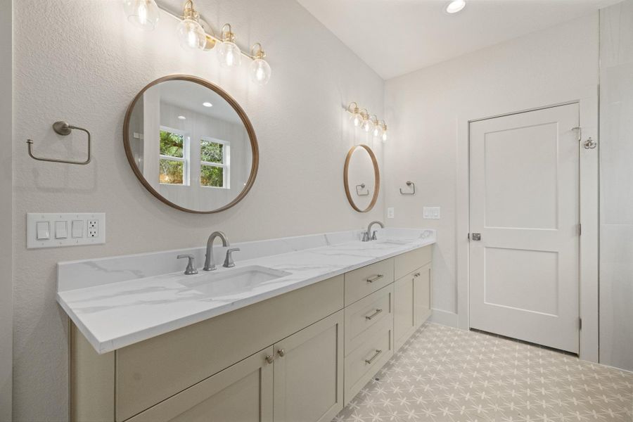Dual vanities with quartz countertops and decorative tile flooring elevate this bathroom's functionality.