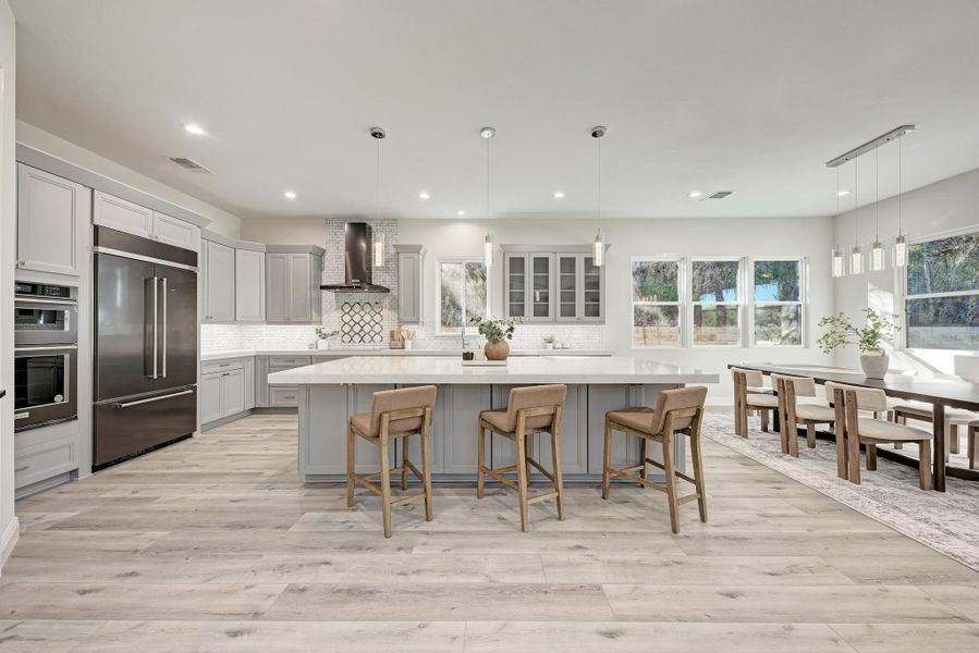 Kitchen featuring a kitchen breakfast bar, pendant lighting, appliances with stainless steel finishes, a center island, and gray cabinetry