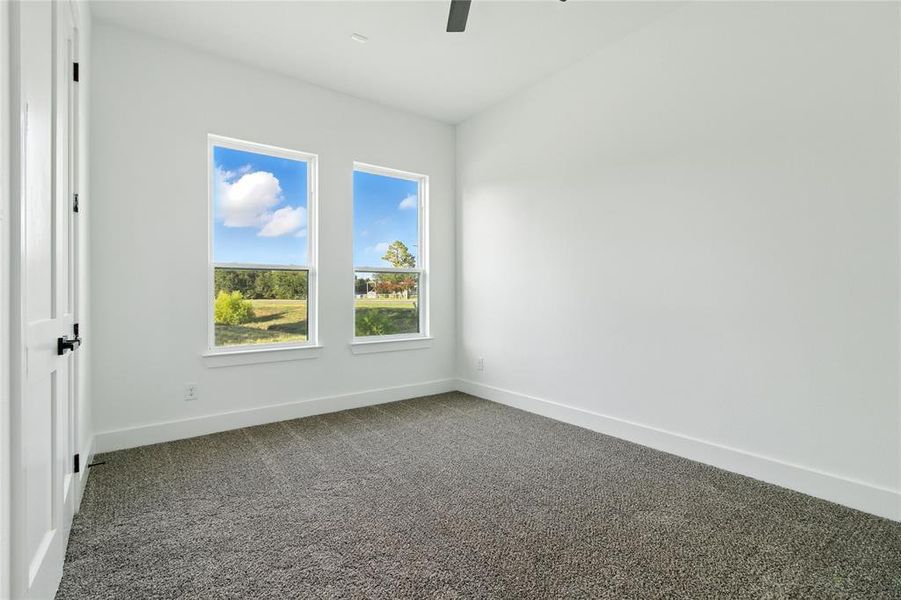 Unfurnished room with dark colored carpet and a ceiling fan Unfurnished room with dark colored carpet and a ceiling fan