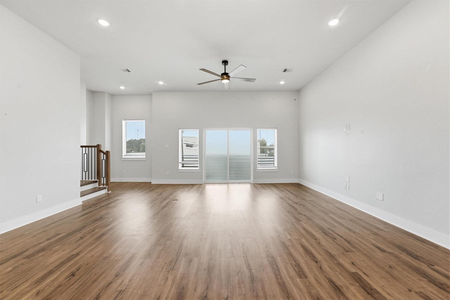 Expansive open living area with wide-plank flooring, recessed lighting, and a wall of windows and sliding doors that fill the space with natural light.