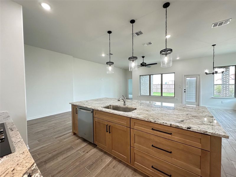 Kitchen featuring light stone countertops, light wood-style floors, recessed lighting, a chandelier, and dishwasher