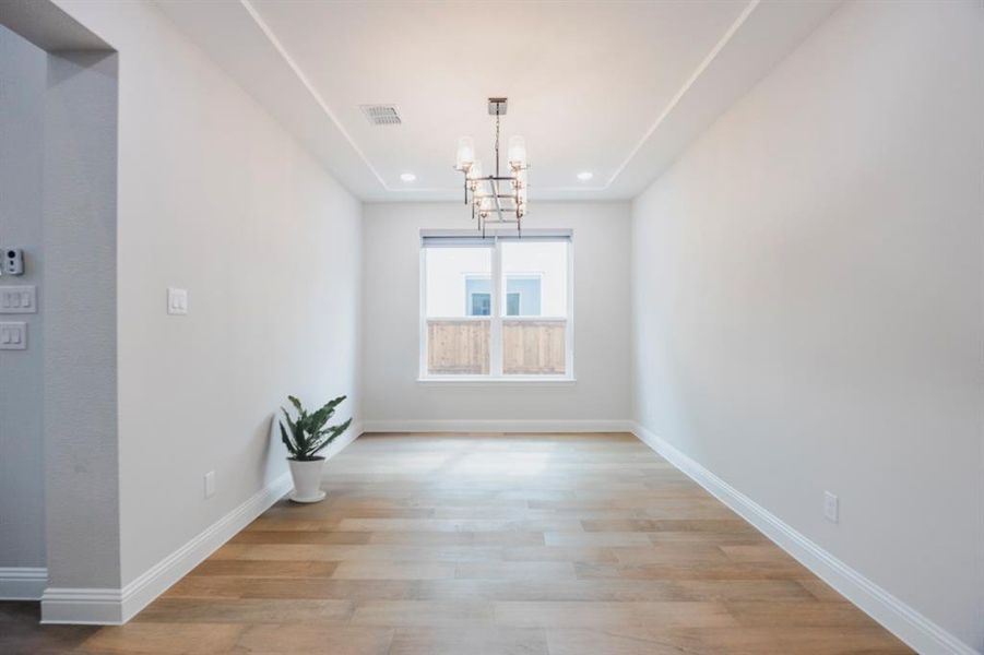 Unfurnished dining area with visible vents, baseboards, an inviting chandelier, and wood finished floors