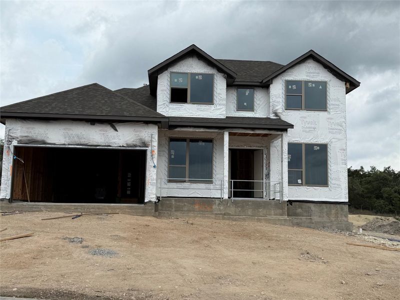 Unfinished property featuring covered porch, a shingled roof, and an attached garage