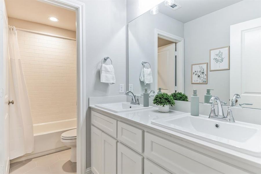 Full bathroom featuring shower / tub combo with curtain, toilet, tile patterned floors, and double vanity