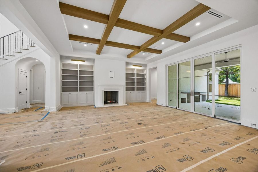The family room includes a wood-burning fireplace with a cast stone mantel, built-ins with an library lights beside the fireplace, and doors by Sierra Pacific that lead to the outdoor living area.