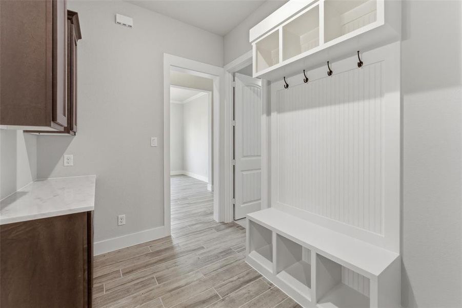 Built-in white mudroom bench with cubby storage, beadboard backing, and black coat hooks