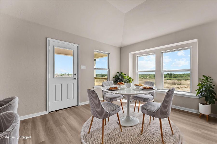 Sun-filled breakfast area with vaulted ceilings and wide-plank flooring offers peaceful outdoor views.