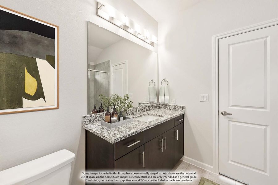 Bathroom with dark wood vanity, granite countertop, single sink, large mirror, and lighted fixture above