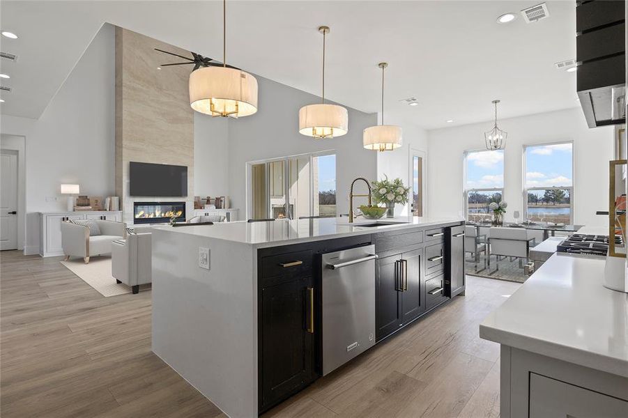 Kitchen featuring light wood-style flooring, visible vents, dishwasher, a sink, and a high end fireplace Kitchen featuring light wood-style flooring, visible vents, dishwasher, a sink, and a high end fireplace