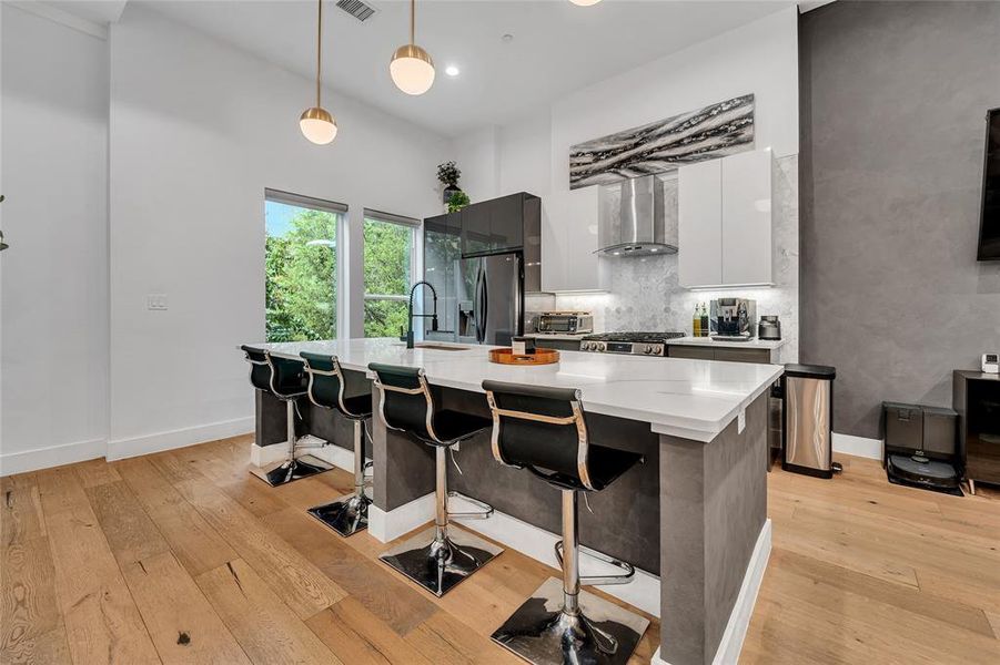 Kitchen featuring pendant lighting, a large island, modern cabinets, a kitchen breakfast bar, and white cabinets Kitchen featuring pendant lighting, a large island, modern cabinets, a kitchen breakfast bar, and white cabinets