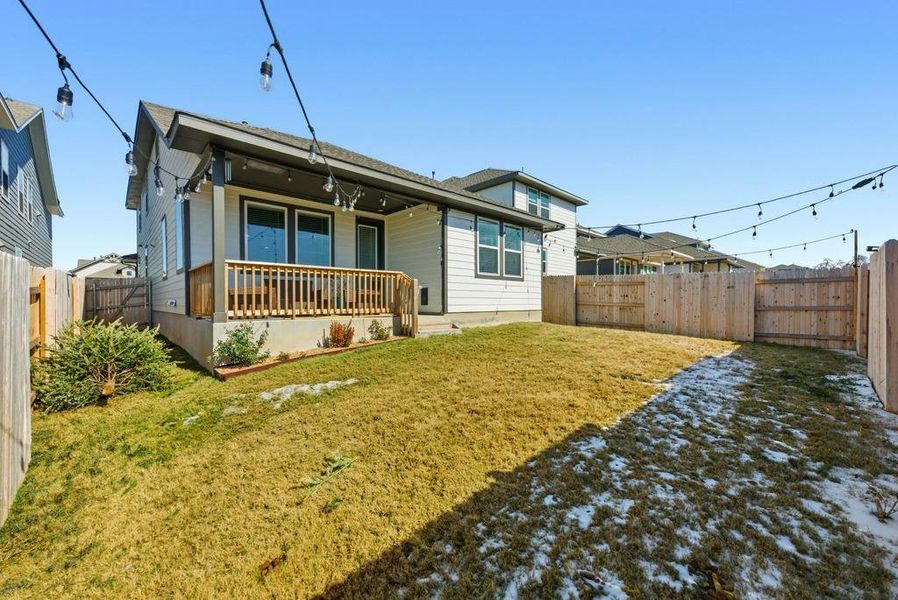 Rear view of house with a fenced backyard and a porch