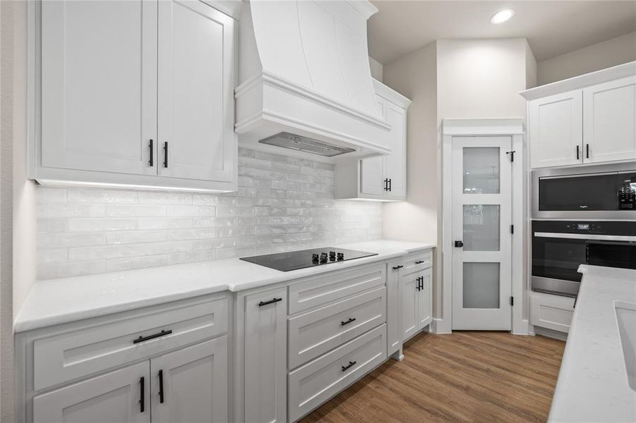 Kitchen with white cabinetry, stainless steel appliances, dark wood-style flooring, decorative backsplash, and light stone counters