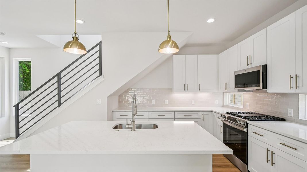 Kitchen with stainless steel appliances, pendant lighting, light stone counters, recessed lighting, and white cabinetry Kitchen with stainless steel appliances, pendant lighting, light stone counters, recessed lighting, and white cabinetry