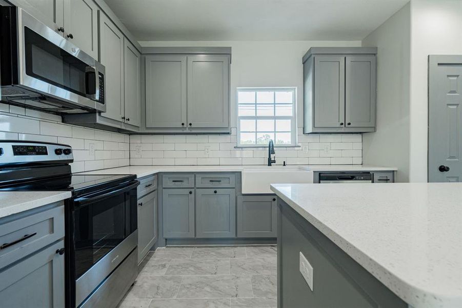 Kitchen with sink, decorative backsplash, appliances with stainless steel finishes, and light tile patterned floors