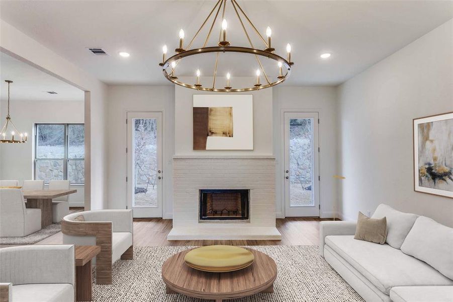 Living room featuring a chandelier, healthy amount of natural light, wood finished floors, a fireplace, and recessed lighting Living room featuring a chandelier, healthy amount of natural light, wood finished floors, a fireplace, and recessed lighting