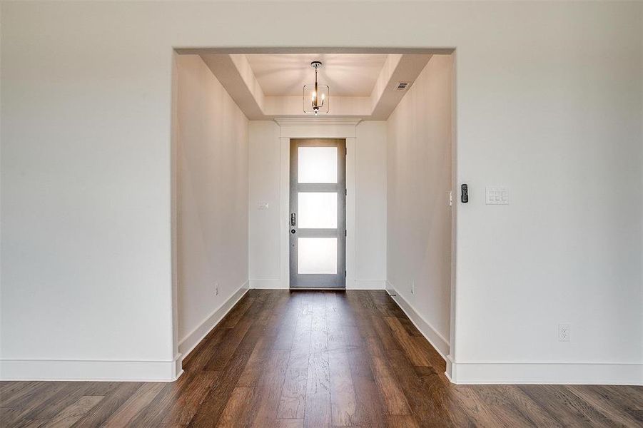 Entryway with dark hardwood / wood-style floors, a notable chandelier, and a tray ceiling