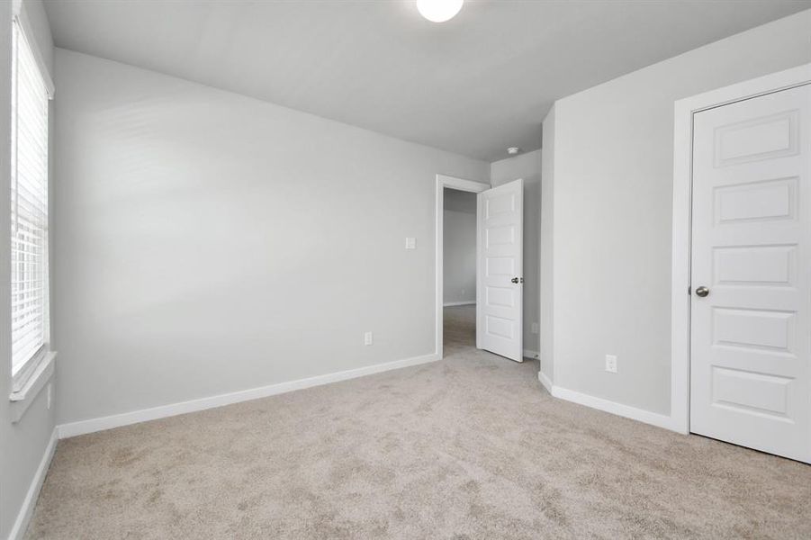 Secondary bedrooms feature elegant 5-panel doors with sleek, contemporary hardware that adds a touch of sophistication. Sink your feet into the plush, fluffy carpet that invites comfort and warmth. Large windows flood the space with an abundance of natural light, framed by privacy blinds that offer the perfect balance between openness and seclusion. Sample photo of completed home with similar floor plan. As-built interior colors and selections may vary.