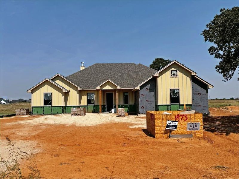 Unfinished property featuring board and batten siding and a shingled roof Unfinished property featuring board and batten siding and a shingled roof