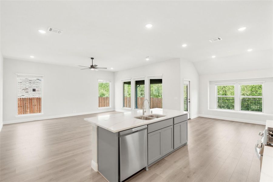 Kitchen island with gray cabinets, sink, and dishwasher open to living area with hardwood floors and ceiling fan Kitchen island with gray cabinets, sink, and dishwasher open to living area with hardwood floors and ceiling fan
