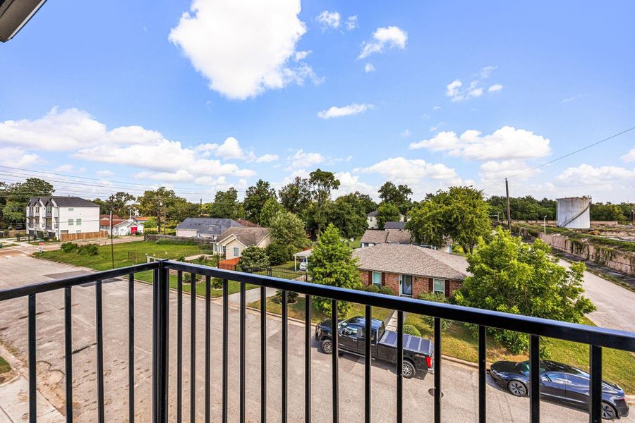 A charming Juliet balcony offering open views through sleek iron railings, framed by beautiful blue skies.