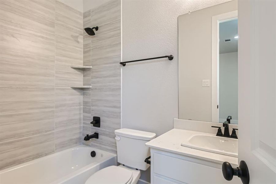 Full bathroom featuring vanity, tiled shower / bath combo, and toilet