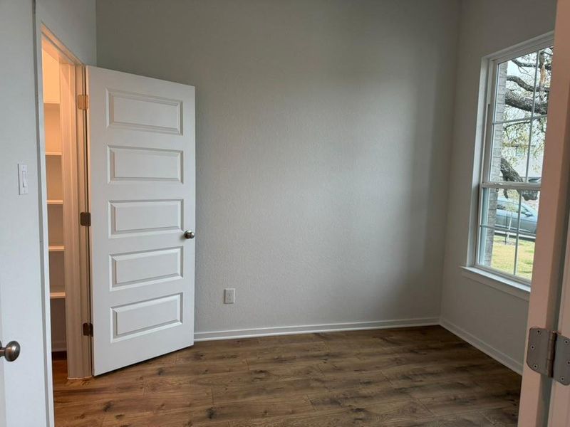 Spare room featuring dark wood-style flooring and baseboards