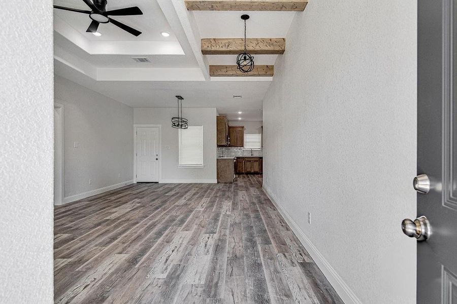 Unfurnished living room with beam ceiling, ceiling fan, and hardwood / wood-style floors