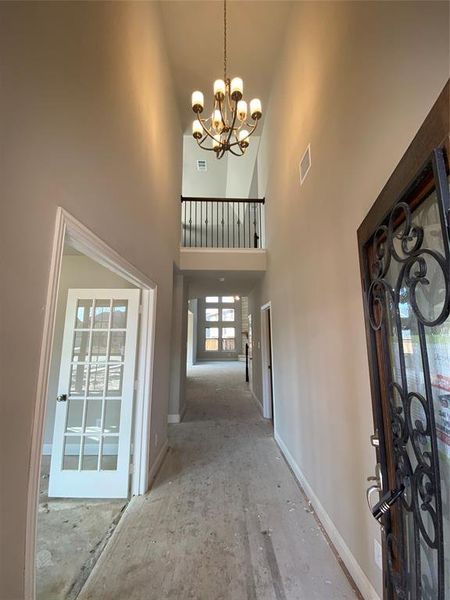 Tall cathedral entry with elegant chandelier and rich hardwood floors (not stained yet.)