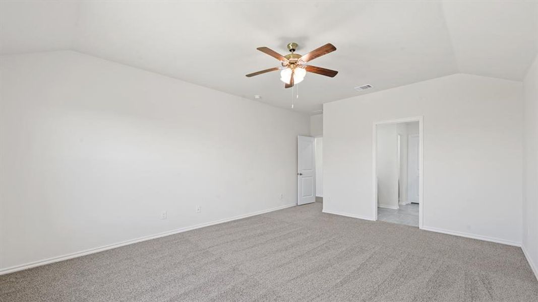 Spacious room featuring vaulted ceilings, light gray carpeting, and a ceiling fan with integrated lighting