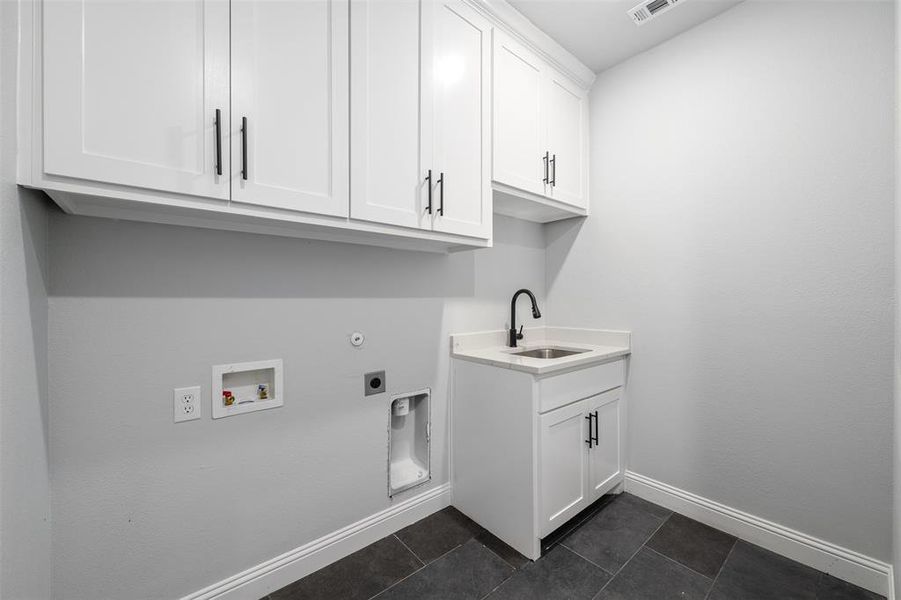 Laundry area with cabinet space, hookup for an electric dryer, hookup for a washing machine, and dark tile patterned flooring Laundry area with cabinet space, hookup for an electric dryer, hookup for a washing machine, and dark tile patterned flooring