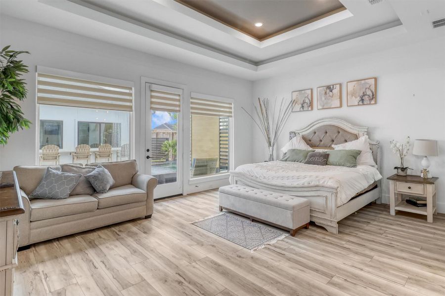 This peaceful primary bedroom is your own private oasis at the end of the day. Notice the detail in the double tray ceiling, recessed lighting, continuous wide plank flooring, large windows, and private entrance out to the pool.
